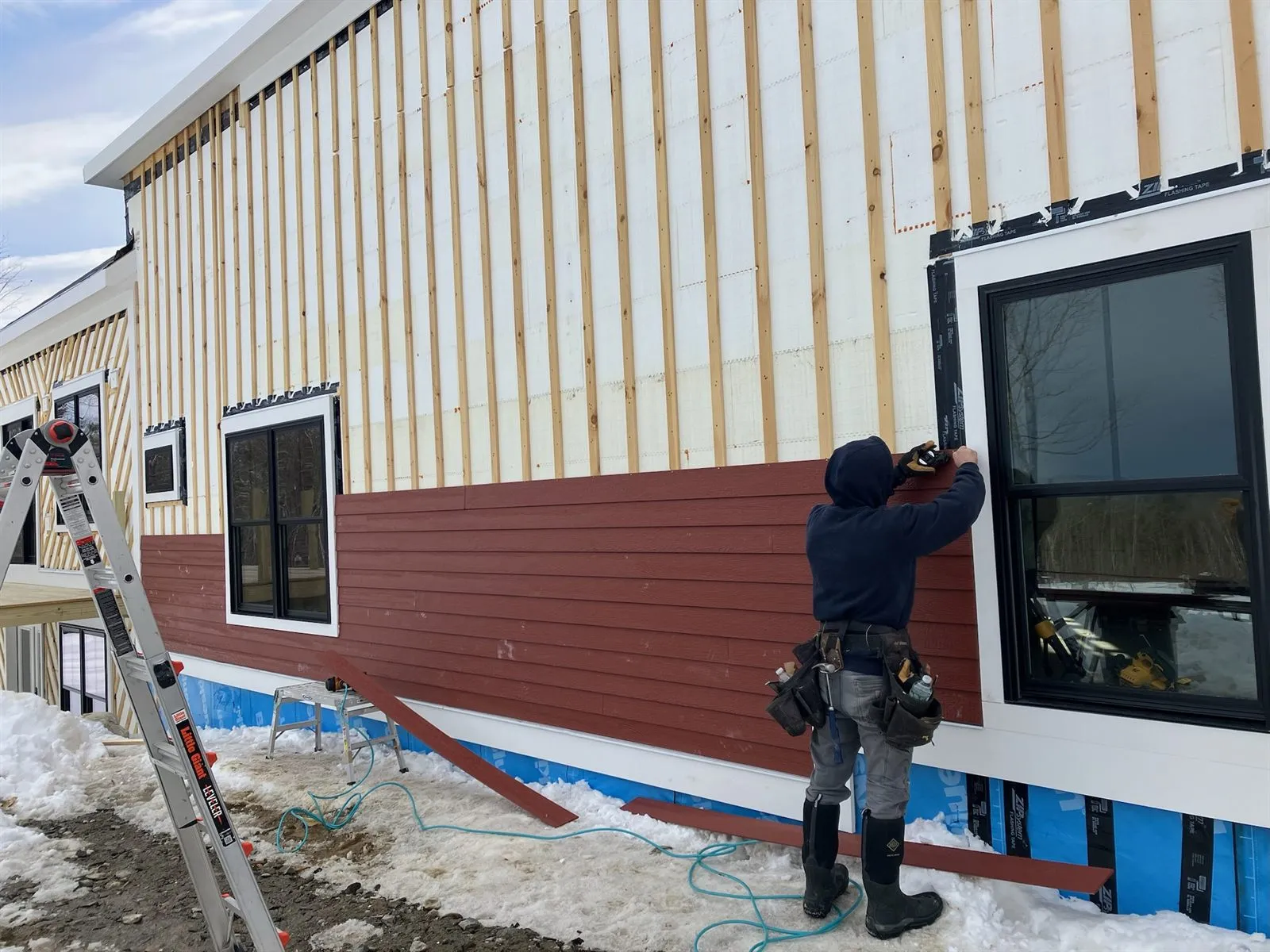 Red clapboard siding going on over furring strips in winter