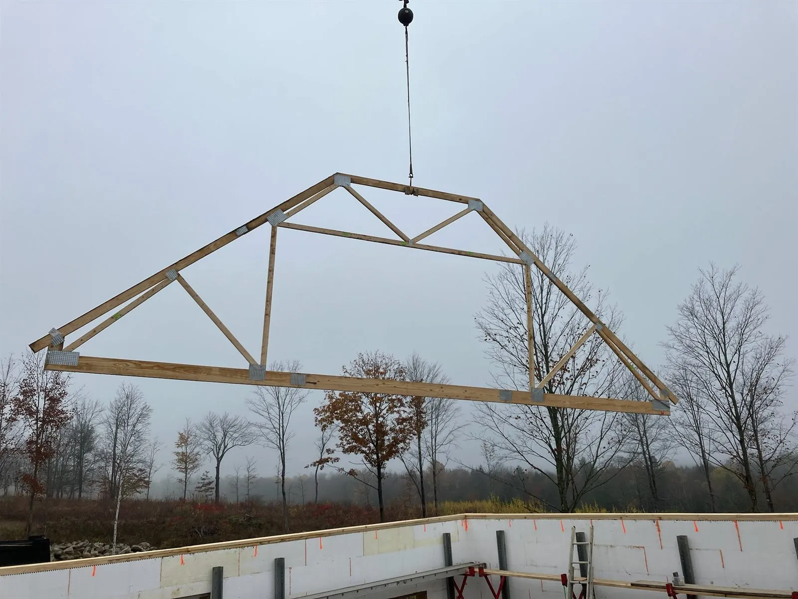 Roof truss hanging from a crane line above the ICF walls