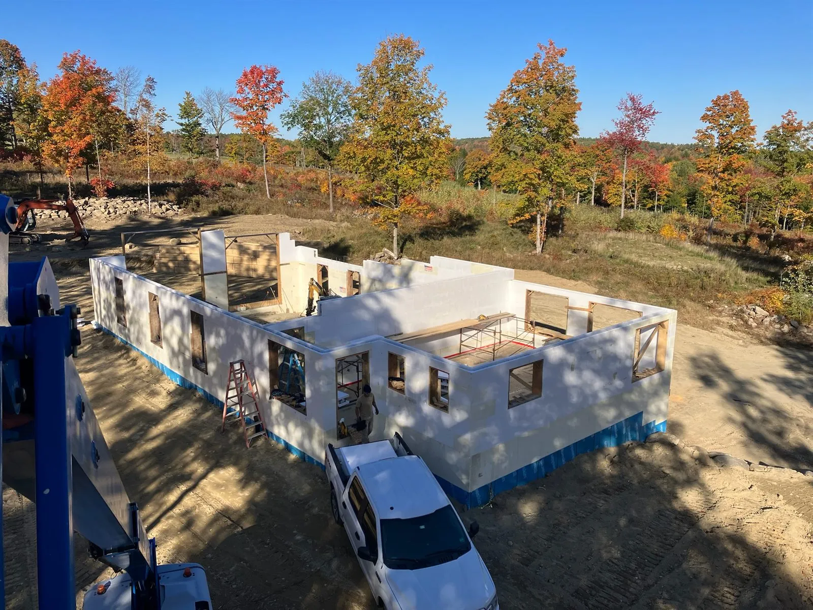 Aerial view of first-floor ICF walls stacked on the foundation, fall foliage behind