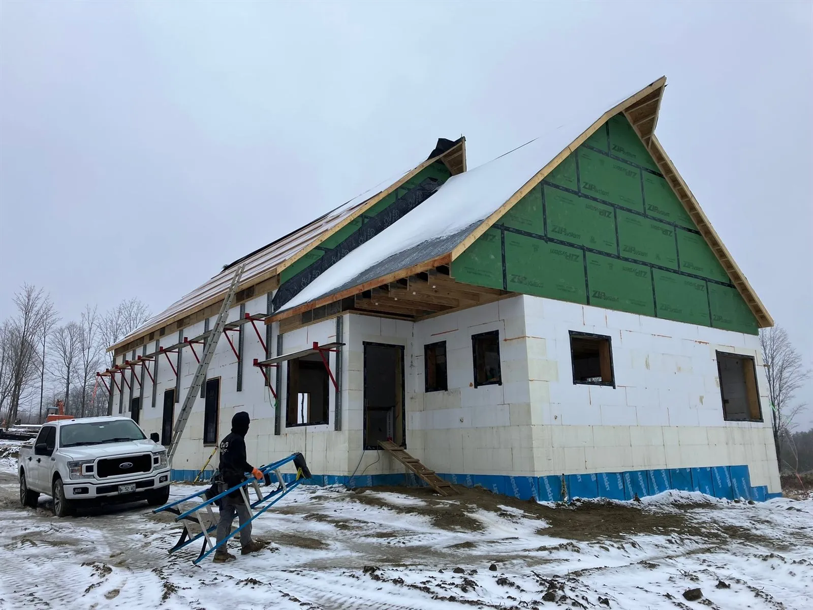 The ICF shell under snow, roof sheathed and wall brackets still up