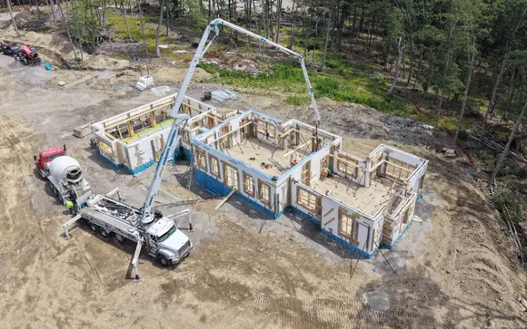 Aerial view of a Mariner Construction ICF home on pour day, with the concrete pump boom reaching over full-height ICF walls