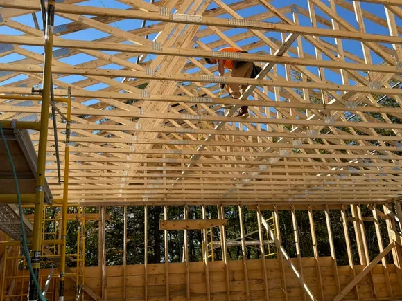 Mariner Construction carpenter setting roof trusses on a framed building
