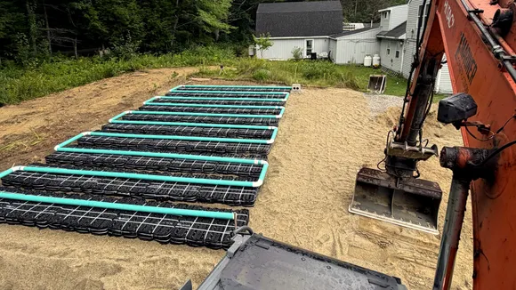 Rows of septic chambers in a fresh sand bed, seen from the cab of a Mariner Construction excavator